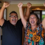 Two people, a man and a woman, smiling and raising their arms in celebration, symbolizing achievement and positivity.